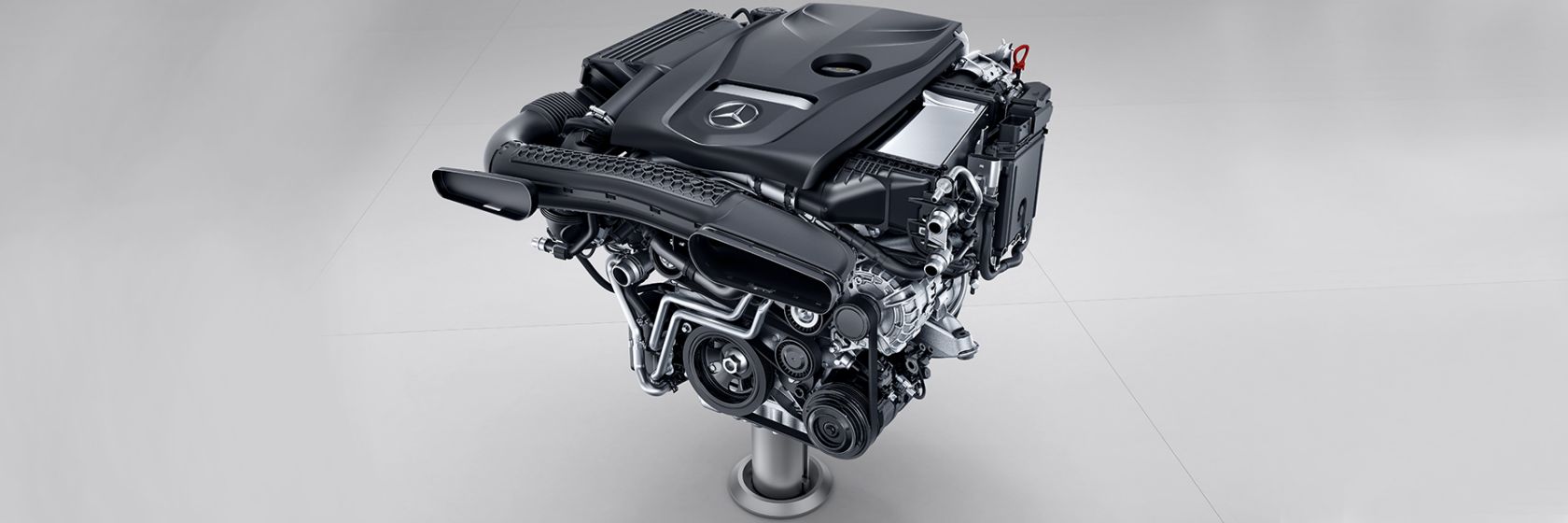 Na obrázku je čtyřválcový zážehový motor vozidla Mercedes-Benz Třídy C kabriolet.